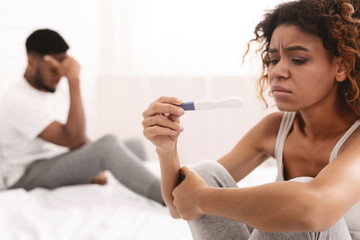 Obraz na płótnie Canvas Thoughtful girl undergoing pregnancy test near boyfriend