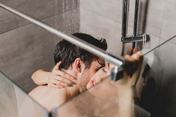 naked man and beautiful woman hugging and kissing in shower cabin