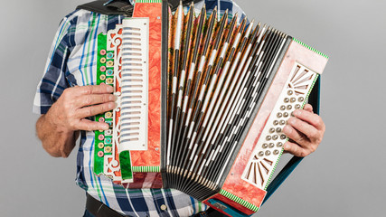 Portrait of a man, grandfather plays the accordion. On a gray background