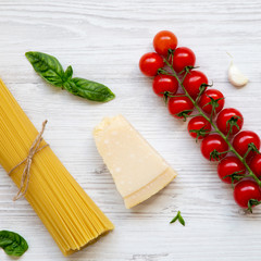 Spaghetti and various ingredients for cooking pasta on a white wooden table, from above. Flat lay. Top view, overhead.