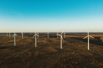 Aerial view of wind turbines blades in the field against the backdrop of a bright orange sunset wind park. Silhouettes of windmills with a bird's-eye view. Alternative energy sources. Drone, slide 