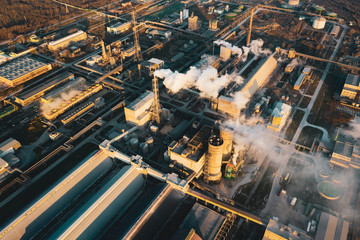 Fototapeta na wymiar Aerial view, the vast territory of a large industrial chemical plant with high pipes in the bright light of winter sunset. Thick smoke comes from a high pipe. Environmental pollution. Drone
