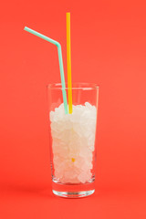 A glass of sugar cubes is a concept of unhealthy food. On red background