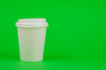 Paper coffee container with white lid on green background. Beverage container take-away. Drink Cup template for your design.