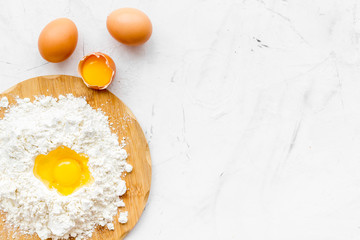 Baking background with eggs and flour on white desk. Top view.