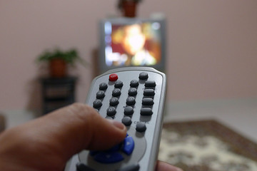a man is changing channel with tv remote,
