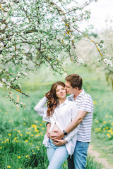 Portrait of lovely future parents during sunset on nature apple tree background