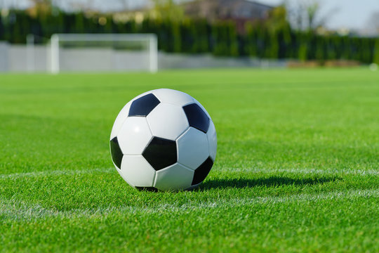 Classic soccer ball lies on the bright green grass on the football field in the designated area of the penalty area against the gate the sports stadium close-up in sports center for football players