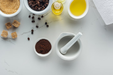 top view of pounder and different natural components in bowls and bottles on white surface