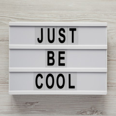Modern board with text 'Just be cool' on a white wooden background, overhead view. From above, flat lay, overhead. Close-up.