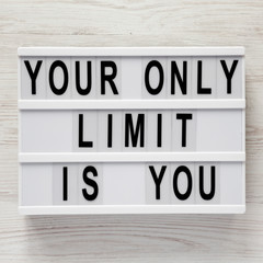 'Your only limit is you' word on modern board on a white wooden surface, top view. From above, flat lay, overhead.