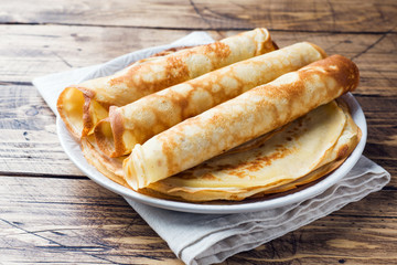 Thin pancakes on a plate. Wooden background. Close up.