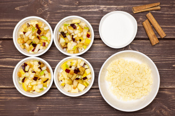 Uncooked chopped mixed fruits step. recipe step by step crumble with fruits in a ceramic ramekin flatlay on brown wood