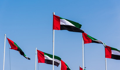 United Arab Emirates flags winding in the wind against blue sky