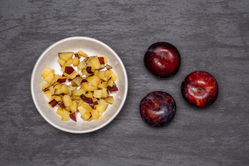 Chopped and mixed plums. recipe step by step crumble with fruits flatlay on grey stone