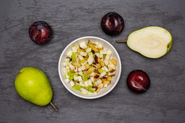 Chopped mixed plums and pears. recipe step by step crumble with fruits flatlay on grey stone