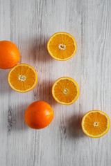 Halved and whole oranges on white wooden table, top view. Overhead, from above, flat lay.