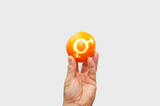 Gender equality. Orange with the sign of gender equality in the hand of a woman. On white background. isolate equality