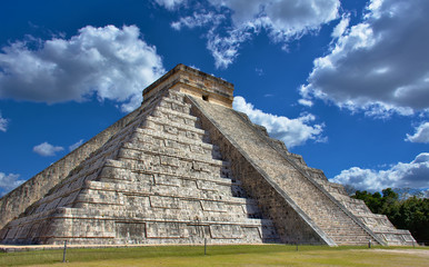Fototapeta na wymiar Sunny day with blue sky and white clouds. No people around. El Castillo (The Kukulkan Temple) of Chichen Itza, mayan pyramid in Yucatan, Mexico - Mar 2, 2018