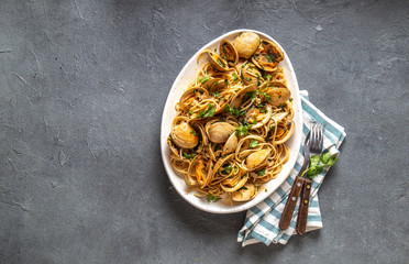 Seafood Pasta. ITALIAN SPAGHETTI ALLE VONGOLE. Clams spaghetti on white plate with white wine, gray background. Top view