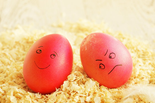Two Easter eggs with the drawn persons. Joyful and the sad broken egg. Traditional game with breaking eggs