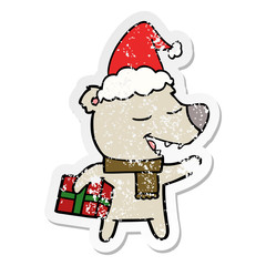 distressed sticker cartoon of a bear with present wearing santa hat