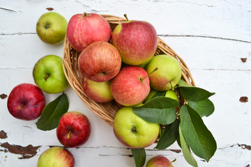 Fresh apples in basket on white wooden background. Harvest time. 