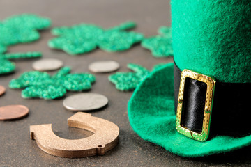 St.Patrick 's Day. celebration. A green leprechaun hat, money and a clover leaf and a horseshoe on a brown background.