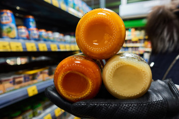 Glass jars of juice in hand on the background of the grocery store
