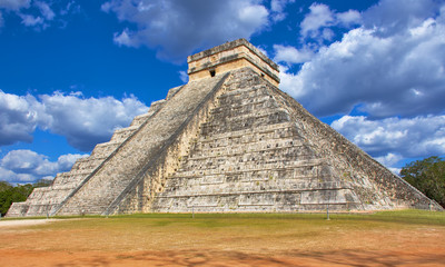 Sunny day with blue sky and white clouds. No people around. El Castillo (The Kukulkan Temple) of Chichen Itza, mayan pyramid in Yucatan, Mexico