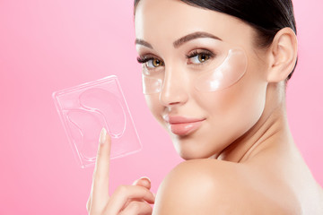 Young girl with nude make up and naked shoulders at studio background, invisible eye patches on...