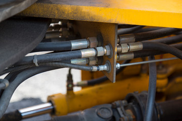 Hydraulic system hoses and other details of yellow road machinery close-up