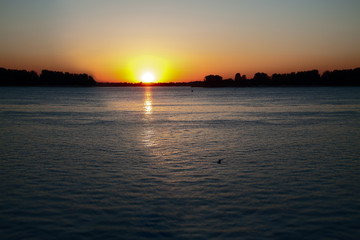 Fototapeta na wymiar Sunset on the river in Nizhny Novgorod. Bright ray of light on the water surface