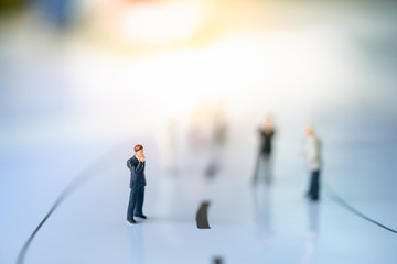 Miniature people: Small businessman figures walking on the street. Business direction, search, leading concepts.
