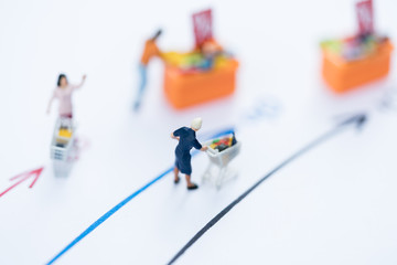 Miniature people: Small old women figures with shopping cart standing on age mile arrow. An aging society and pension concepts.