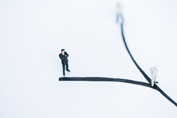 Miniature people: Small businessman figures standing on turning poing. The concept of role conflict...