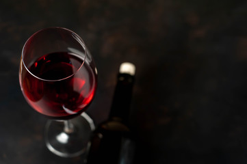 A bottle of wine and a glass of wine against a concrete background. Top view with copy space.
