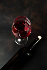Bottle of wine and a glass of wine on a concrete background