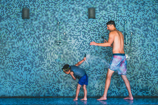 Father and son playing with water in an open shower