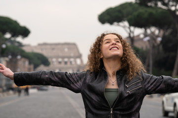 Happy young woman enjoys her visit to Rome, Italy, in front of the coliseum