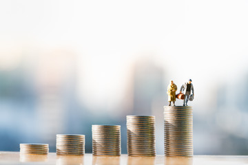 Concepts of retirement planning and finanacial. Miniature people: Old couple figure standing on top...