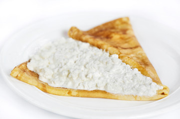 Thin delicious pancake with cottage cheese on white