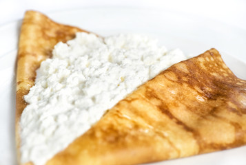 Thin delicious pancake with cottage cheese on white