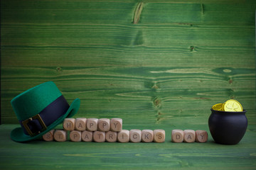 Happy St Patricks Day wooden blocks with leprechaun hat on a wooden background