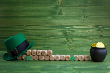 Happy St Patricks Day wooden blocks with leprechaun hat on a wooden background