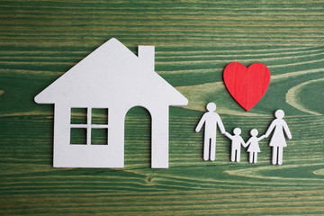 Family figure with a house on green wooden background