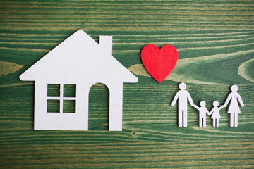 Family figure with a house on green wooden background