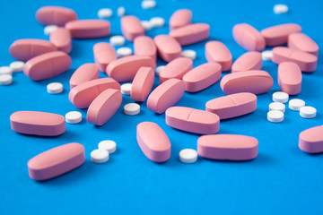 Obraz na płótnie Canvas White and pink pills on blue background. Medicine and healthcare concept