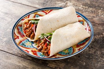 Typical Mexican burrito wrap with beef, frijoles and vegetables  on wooden table