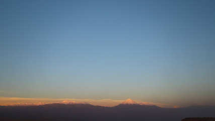 Fototapeta na wymiar View of the landscape of rocks of the Mars Valley (Valle de Marte) and snow-covered volcanoes at sunset, Atacama Desert, Chile